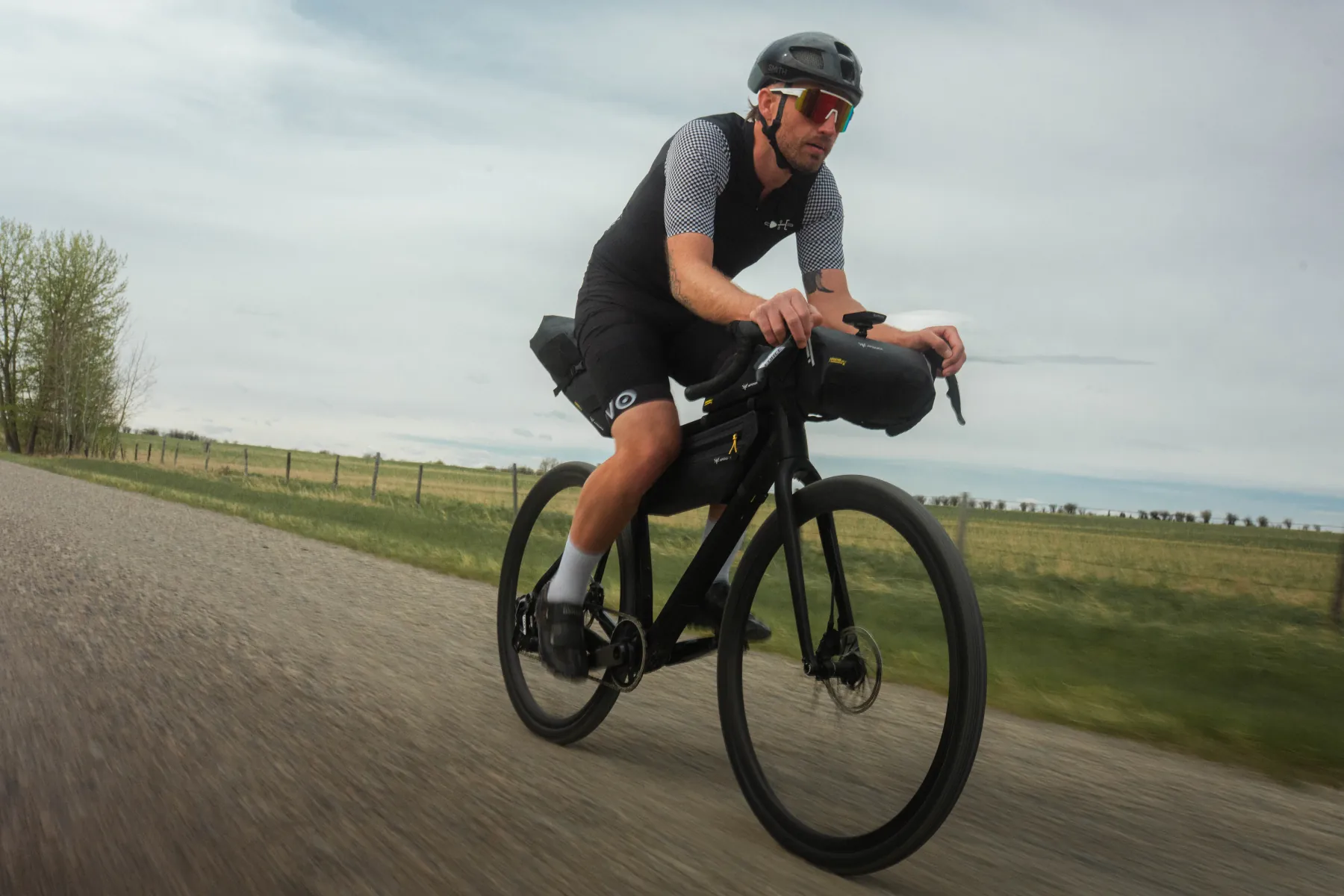 Cyclist riding a gravel road fully loaded with Apidura Expedition packs