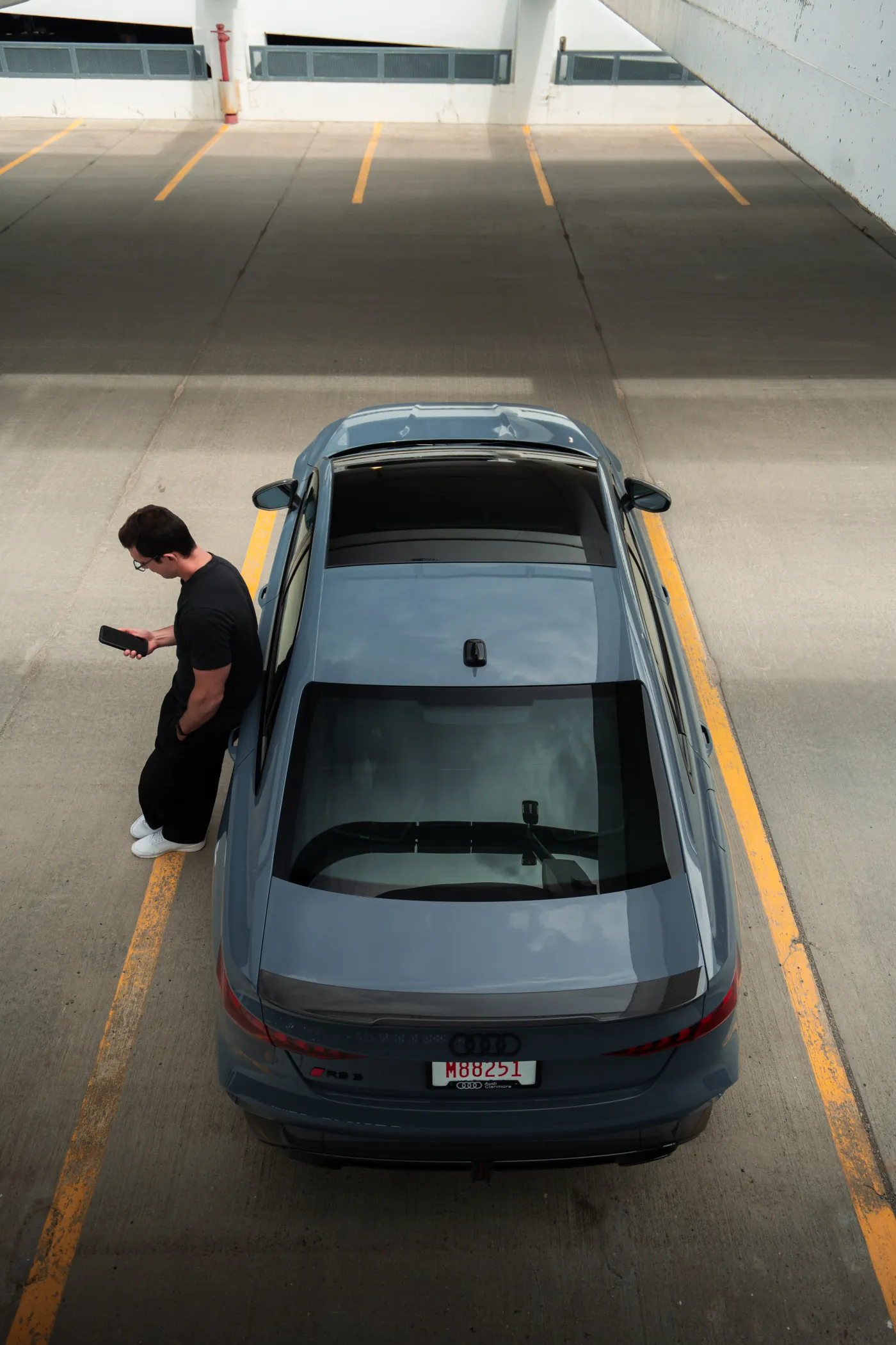 Top-down view over the Audi RS3's roof as the driver waits beside it