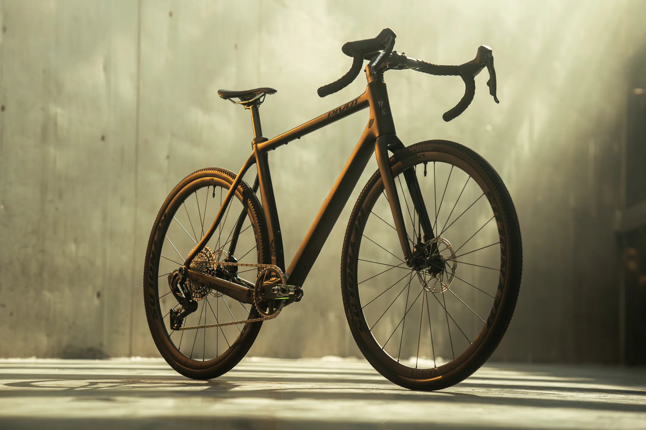 Pivot gravel bike in golden light against a concrete wall, studio-style product shot