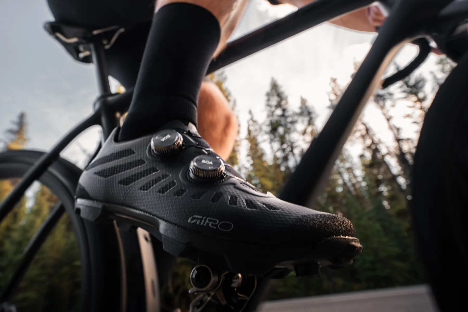 Close-up of a rider's Giro shoe clipped in on the Pivot, forest light behind