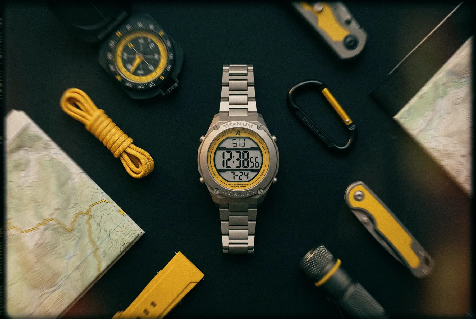 Flat lay of the RZE titanium watch with maps, compass and expedition tools