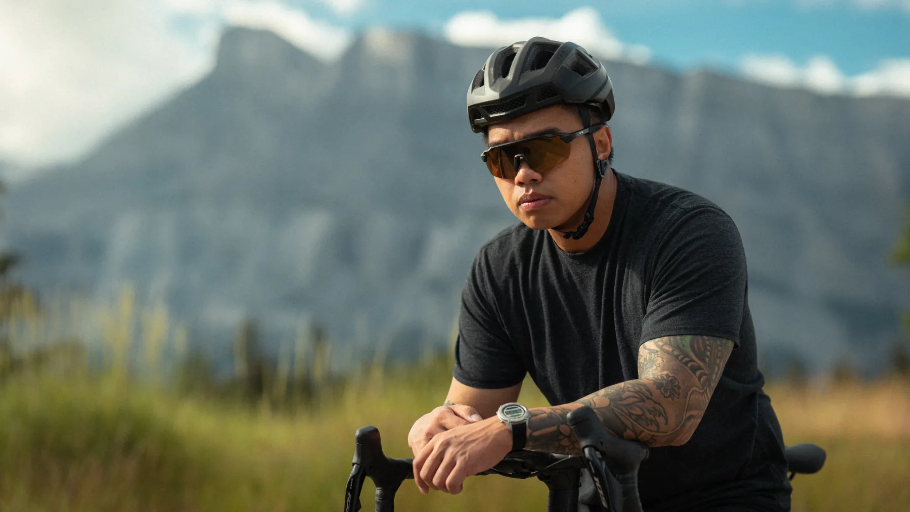Rider in Spek glasses resting on the bars, mountain wall behind