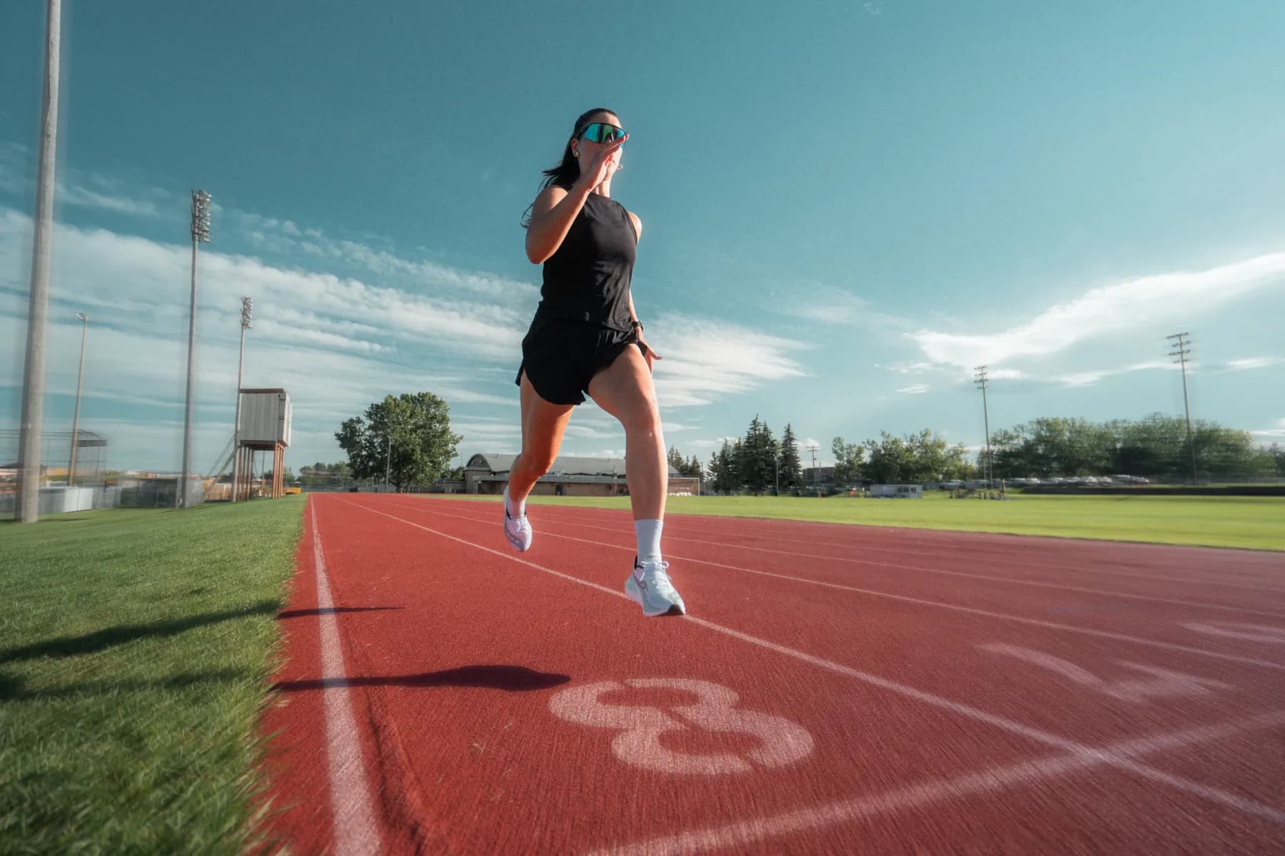 Track-level shot of a runner in Spek glasses powering over the lane numbers